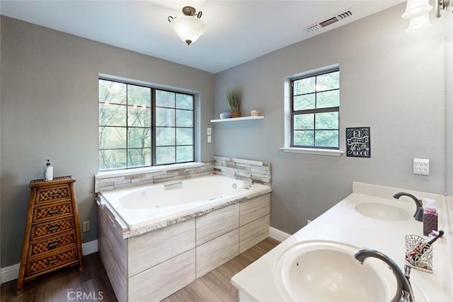 full bath featuring a bath, visible vents, a sink, and wood finished floors