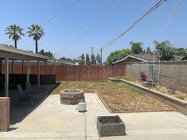 view of yard with a garden, a patio area, fence, and a fire pit