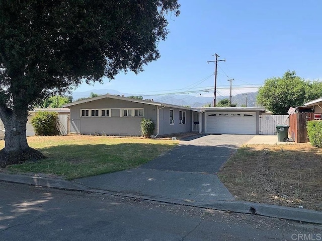 ranch-style house with a garage, concrete driveway, fence, and a front lawn