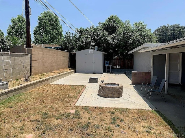 view of yard with an outbuilding, an outdoor fire pit, a fenced backyard, a shed, and a patio area