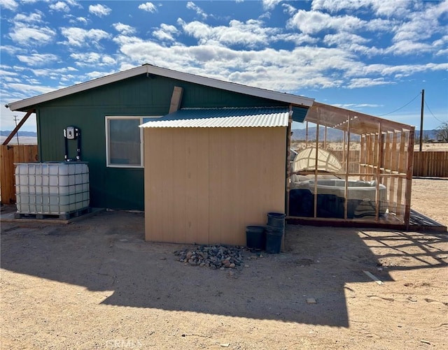 view of side of property featuring metal roof and fence