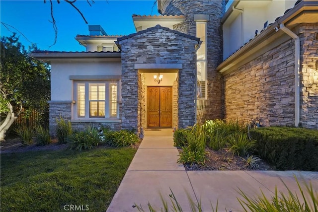 doorway to property featuring stone siding and stucco siding