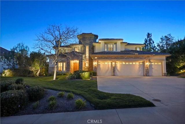 mediterranean / spanish-style house with an attached garage, a front lawn, stucco siding, stone siding, and driveway