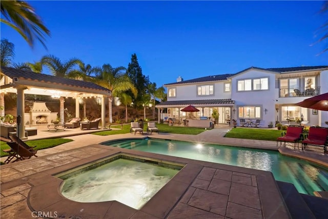 pool featuring a patio, an in ground hot tub, and an outdoor living space with a fireplace