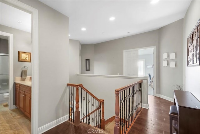 corridor with wood finished floors, recessed lighting, an upstairs landing, and baseboards