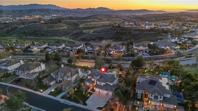 aerial view at dusk featuring a mountain view and a residential view