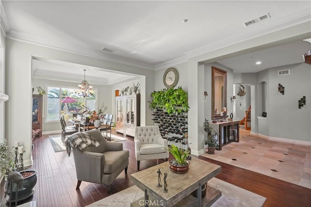 living room featuring arched walkways, visible vents, ornamental molding, and wood finished floors