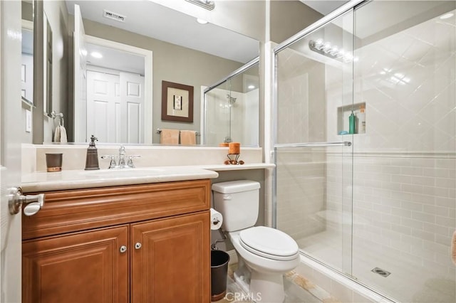 bathroom with visible vents, a shower stall, toilet, and vanity