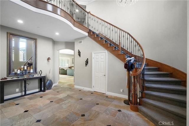 stairs with visible vents, baseboards, recessed lighting, a high ceiling, and arched walkways