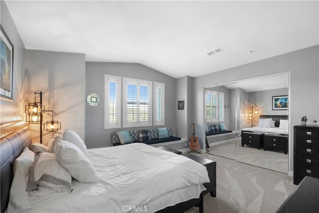 carpeted bedroom featuring a closet, visible vents, baseboards, and lofted ceiling