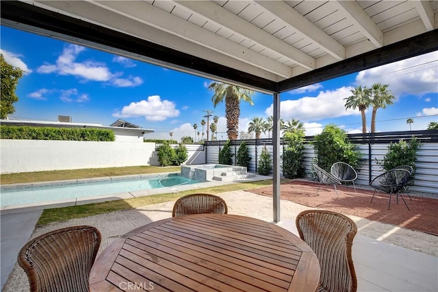 view of patio / terrace with outdoor dining space, a pool with connected hot tub, and a fenced backyard