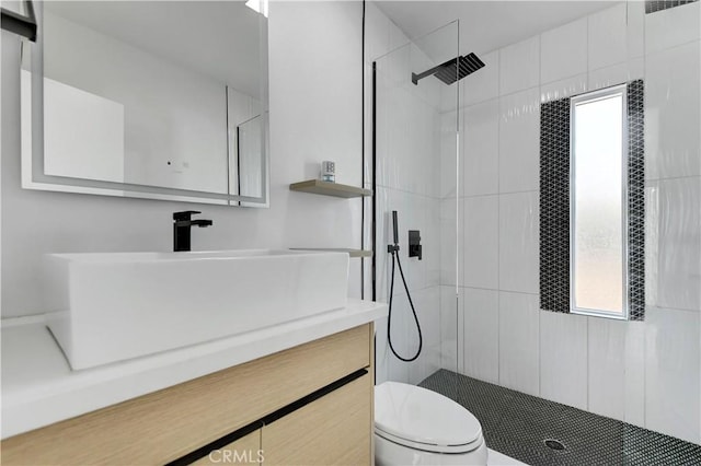 full bath with toilet, a tile shower, and vanity