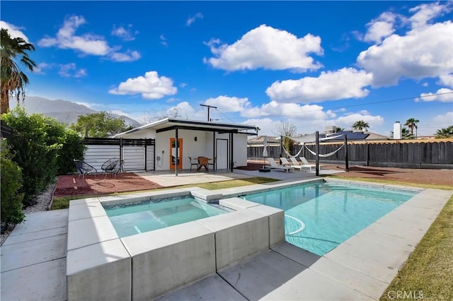 view of pool with a pool with connected hot tub, a patio area, a mountain view, and a fenced backyard