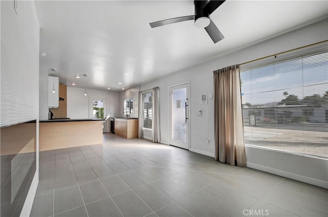 unfurnished living room featuring light tile patterned floors, baseboards, ceiling fan, a sink, and recessed lighting