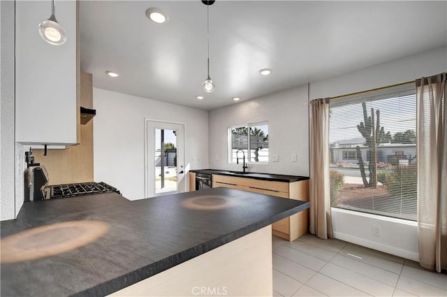 kitchen with plenty of natural light, dark countertops, a sink, and a peninsula