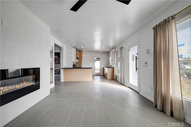 unfurnished living room featuring light tile patterned floors and a glass covered fireplace