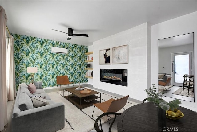 living room featuring wallpapered walls, baseboards, a glass covered fireplace, a wall unit AC, and ceiling fan