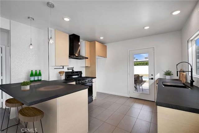 kitchen with dark countertops, black gas range, a sink, a peninsula, and wall chimney exhaust hood