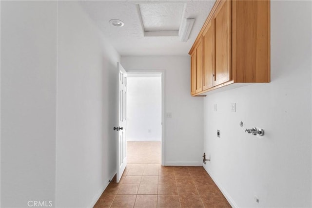 laundry area featuring cabinet space, hookup for a gas dryer, a textured ceiling, hookup for an electric dryer, and light tile patterned flooring