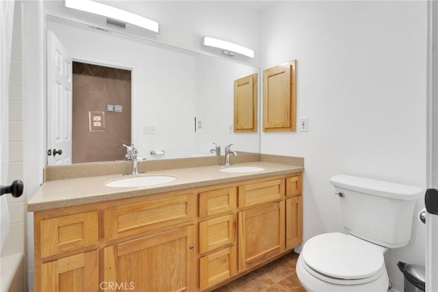 bathroom with toilet, a sink, double vanity, and tile patterned floors