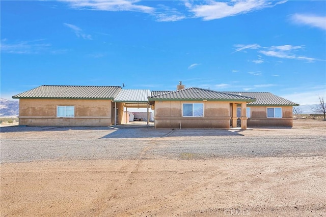 view of front of property featuring a tile roof, an attached carport, driveway, and stucco siding