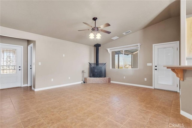 unfurnished living room featuring ceiling fan, visible vents, baseboards, vaulted ceiling, and a wood stove