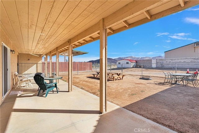 view of patio / terrace with a fenced backyard, outdoor dining space, and a mountain view