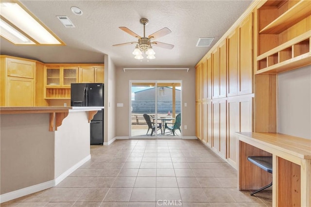 kitchen featuring light tile patterned flooring, open shelves, freestanding refrigerator, a kitchen breakfast bar, and ceiling fan