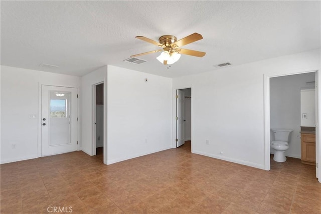 unfurnished bedroom featuring baseboards, a textured ceiling, ensuite bath, and visible vents