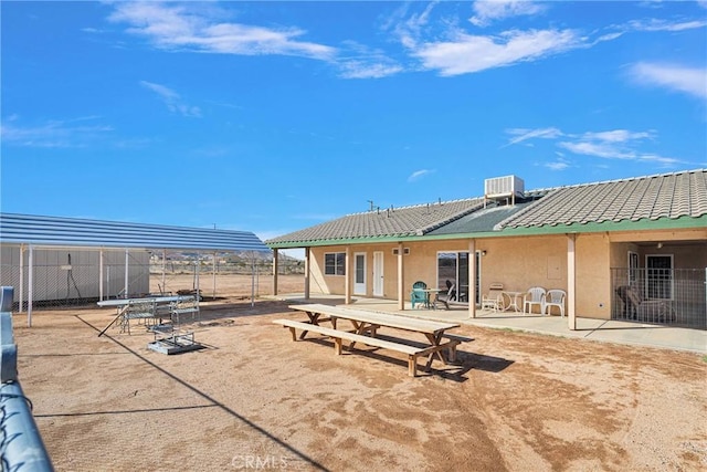 rear view of property featuring a patio, a tile roof, fence, central air condition unit, and stucco siding