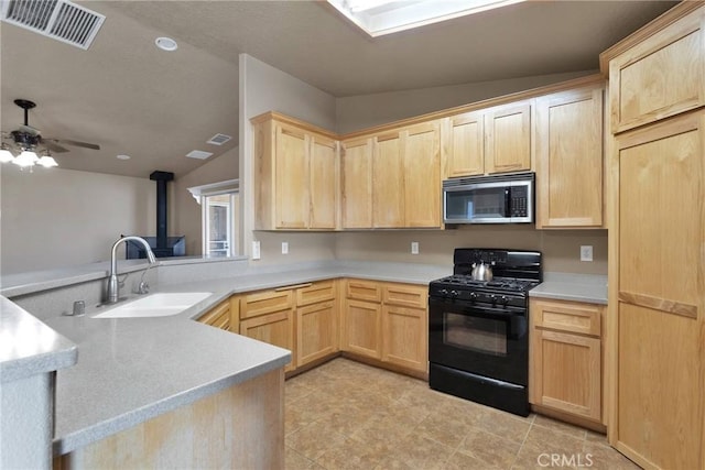 kitchen featuring stainless steel microwave, a sink, black gas stove, visible vents, and light brown cabinets