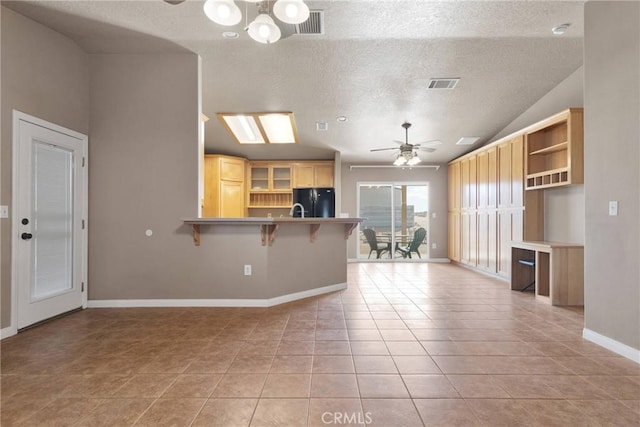 kitchen featuring light tile patterned floors, ceiling fan with notable chandelier, a peninsula, visible vents, and freestanding refrigerator