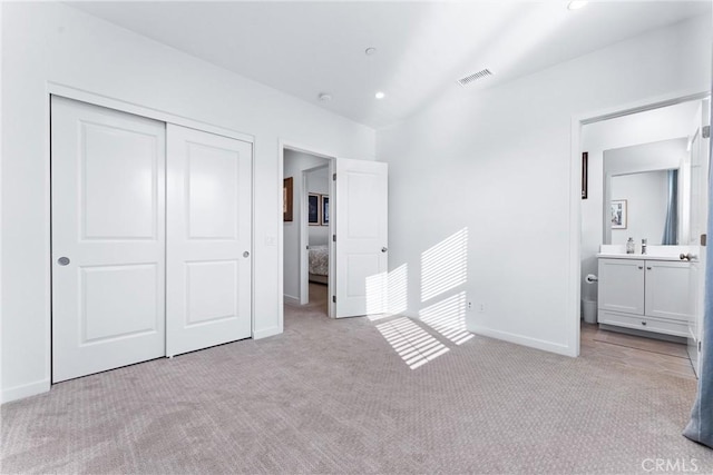 unfurnished bedroom featuring baseboards, a closet, visible vents, and light colored carpet