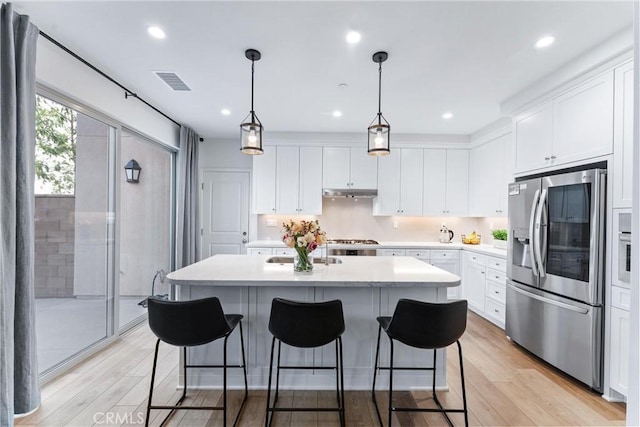 kitchen featuring a center island with sink, visible vents, light wood-style flooring, white cabinetry, and stainless steel fridge with ice dispenser