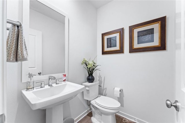 half bathroom featuring a sink, toilet, and baseboards