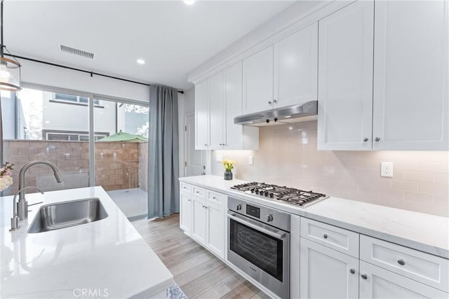 kitchen featuring under cabinet range hood, stainless steel appliances, a sink, white cabinetry, and visible vents