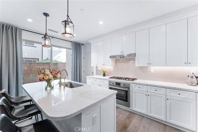 kitchen featuring visible vents, stainless steel appliances, light wood-type flooring, under cabinet range hood, and a sink