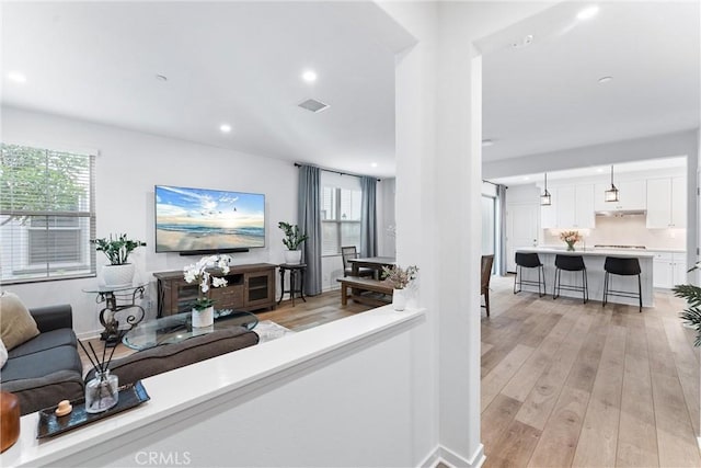 living room with baseboards, light wood finished floors, visible vents, and recessed lighting