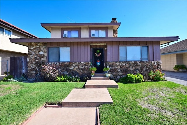 view of front of home featuring board and batten siding, stone siding, a chimney, and a front lawn