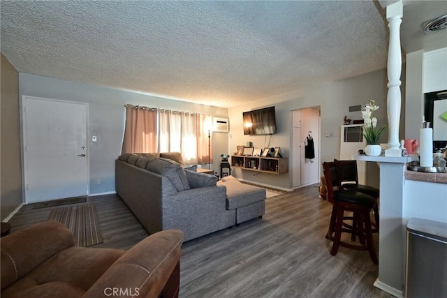 428 N Garfield Ave, Alhambra, CA 91801 - living room featuring a textured ceiling, visible vents, dark wood-style floors, a wall mounted air conditioner, and decorative columns