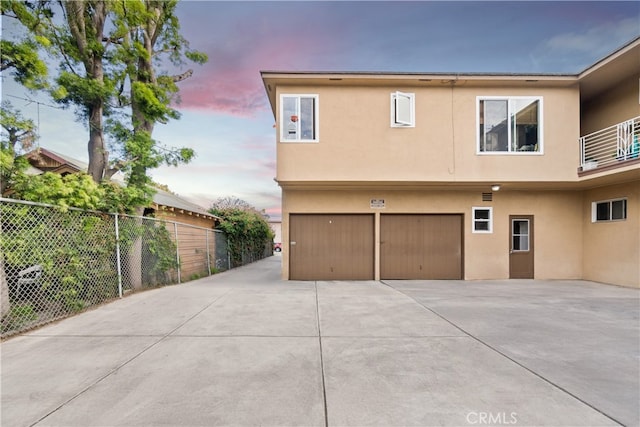 exterior space featuring a garage, driveway, fence, and stucco siding