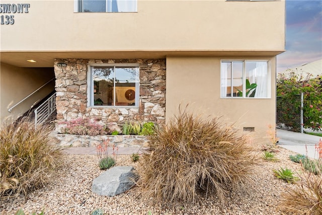 exterior space featuring crawl space, stone siding, and stucco siding