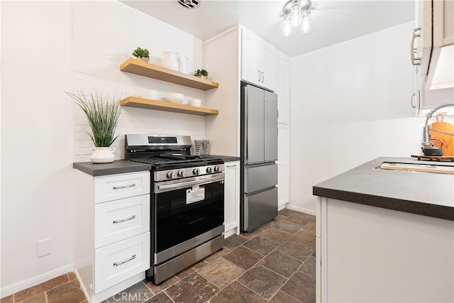 kitchen with appliances with stainless steel finishes, dark countertops, a sink, and stone tile flooring