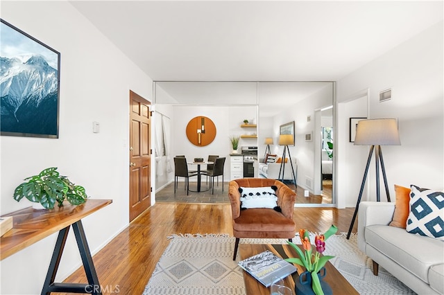 living area featuring light wood-style flooring, visible vents, and baseboards