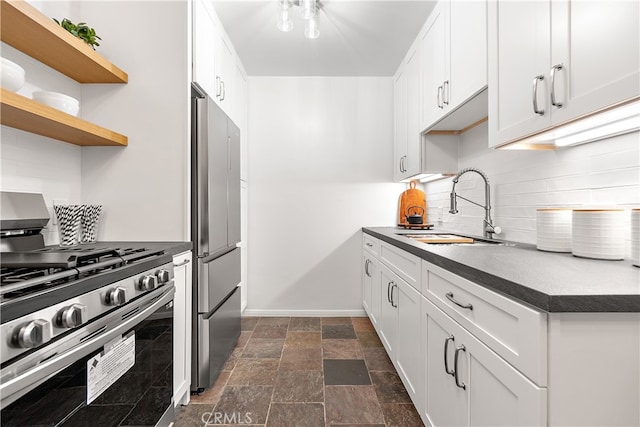 kitchen featuring backsplash, appliances with stainless steel finishes, stone finish floor, white cabinets, and a sink