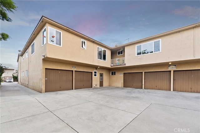 rear view of house featuring an attached garage, driveway, and stucco siding