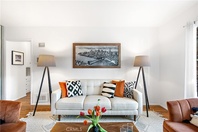 living area with baseboards, visible vents, and wood finished floors