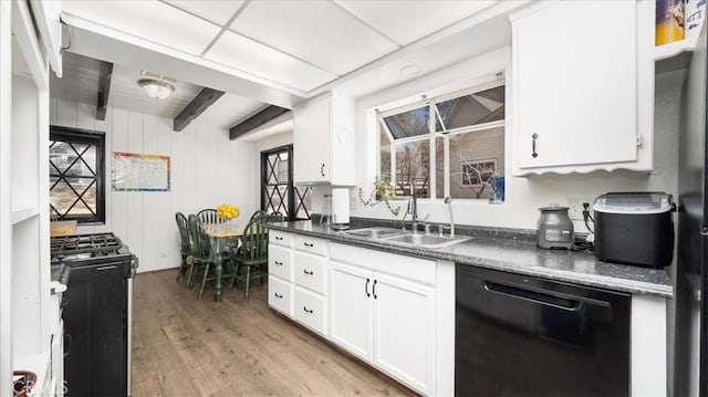 kitchen featuring dark countertops, dishwasher, light wood-type flooring, white cabinetry, and a sink