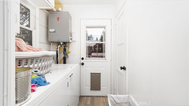 washroom with tankless water heater, light wood-style flooring, laundry area, and washer and clothes dryer