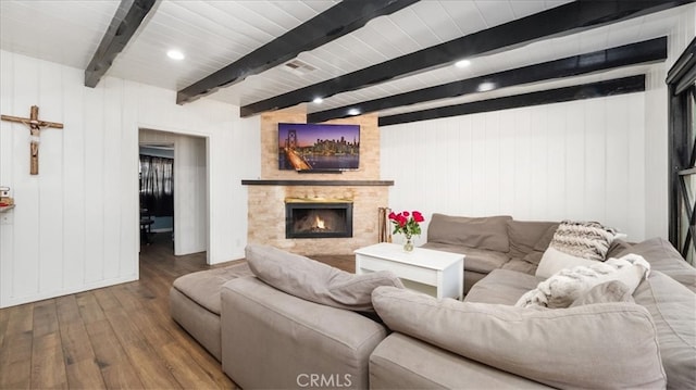 living area with a large fireplace, beam ceiling, and wood finished floors